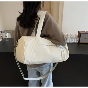 Detail of cream white cylinder yoga bag showing nylon texture and adjustable strap