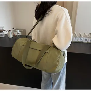 Olive green nylon cylinder yoga bag shown in a lifestyle gym setting with shoulder strap