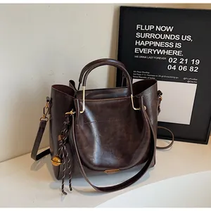 Detailed view of brown tote bag featuring golden hardware and braided rope charm