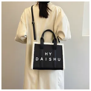 Dettaglio di una borsa tote nera con bordo in agnellino bianco e scritte HY DAISHU