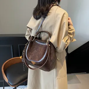 Brown high-shine leather tote bag with gold triangle detail and dual handles