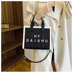 Dettaglio borsa tote in pelle nera con bordo in pelliccia sintetica bianca e scritta HY DAISHU