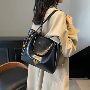Elegant black glossy leather tote bag with gold triangle detail and tassel for daily commute