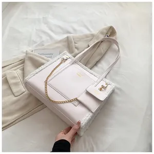 Detail of faux shearling trim tote bag with mini zippered pouch and gold chain link