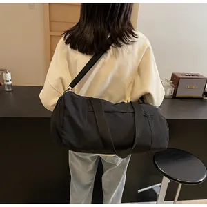 Detail of a large black cylinder yoga bag with adjustable strap and side drawstring features