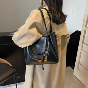 Classic black PU leather tote bag with gold triangle plaque shown on model in khaki coat