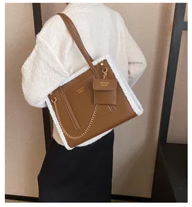 Detail of brown leather tote bag with white faux fur trim and gold chain accessories