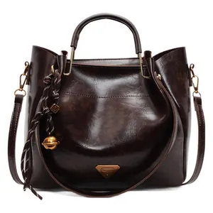 Dark brown faux leather tote bag with round handles and gold-tone hardware on white background