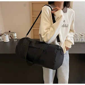 Close-up of a large black cylindrical sports bag with adjustable straps and side zipper pocket
