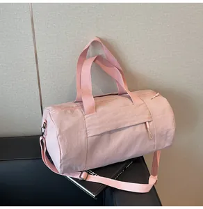 Detail of pink cylindrical gym bag showing waterproof nylon fabric and adjustable strap