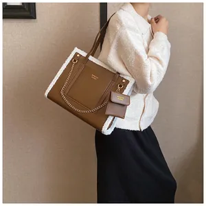 Macro detail of brown leather tote with white faux fur trim and gold chain ornament