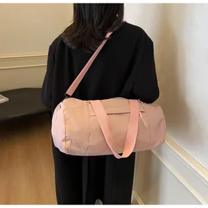 Detailed view of pink cylinder yoga bag with adjustable strap worn by a model