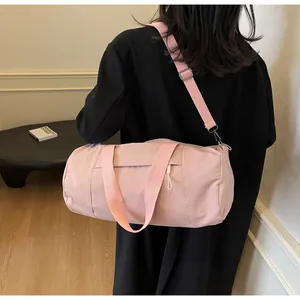 Pink cylinder yoga bag with adjustable strap worn by model against a black coat