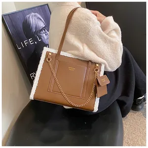 Detail of brown faux leather tote with white plush trim, gold chain, and mini pouch