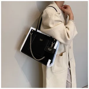 Detail of black leather and white faux fur trim on a large tote bag with gold chain strap