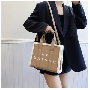 Dettaglio della borsa tote in pelle kaki con bordo in pelliccia sintetica e logo HY DAISHU