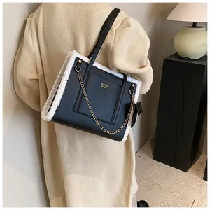 Detailed close-up of black leather tote with white faux fur trim and gold chain detail
