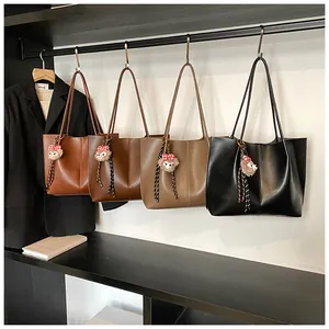 Close-up of stylish faux leather tote bags in four colors with cute plush pendants