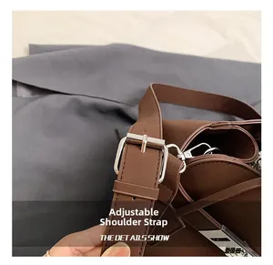 Detail shot of the adjustable shoulder strap with silver buckle on brown leather tote