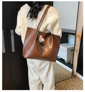 Detailed back view of a dark brown tote bag with a plush lamb charm on a model