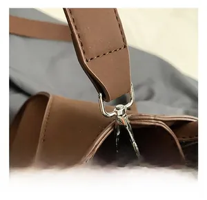 Close-up of premium silver metal hook and reinforced stitching on brown leather shoulder bag