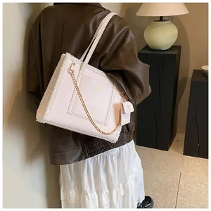 Detail of pink faux leather tote bag with white faux fur trim and gold chain strap