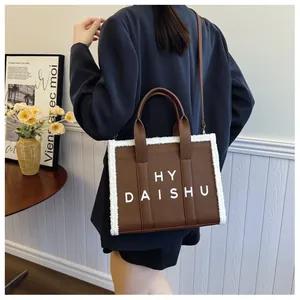 Borsa tote marrone con bordo in shearling bianco mostrata su modella in ambiente casa