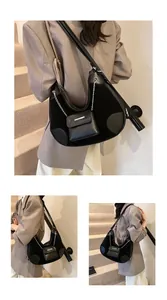 Detalle del bolso hobo de media luna negra con cadena de plata y mini colgante