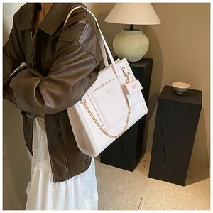 Detail of faux shearling tote bag with gold chain accent and mini pouch attachment