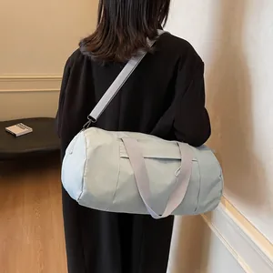 Light blue cylinder yoga gym bag with gray straps shown in a minimalist lifestyle setting
