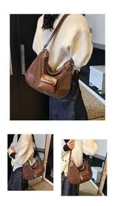 Detalle de bolso hobo marrón oscuro con costuras de ante y minibolso con cadena metálica