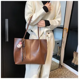 Brown large capacity tote bag with bear charm shown in a cozy indoor lifestyle setting