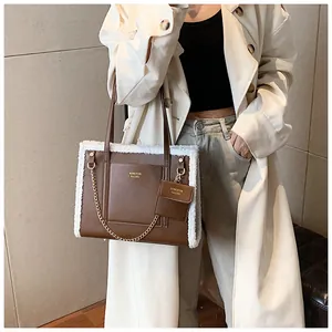 Detail of brown faux leather tote with white shearling trim and chain shoulder strap