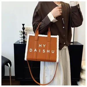 Dettaglio della borsa tote caramello con bordo in shearling e scritte HY DAISHU