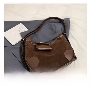 Detalle de bolso medialuna de ante marrón oscuro con cadena de metal y monedero pequeño