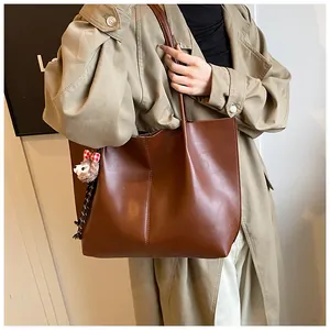 Brown matte PU leather tote bag detail with plush alpaca charm and vertical stitching