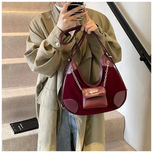 Detalle de bolso hobo de terciopelo granate con cadena plateada y mini estuche a juego