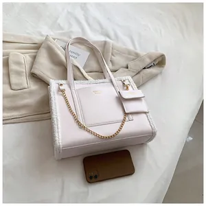 Detail of pink faux leather tote bag with white faux shearling trim and gold chain detail
