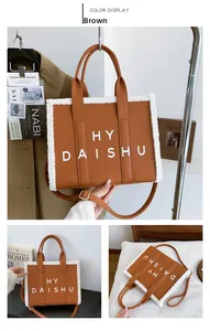Dettaglio borsa tote marrone con bordo in pile bianco e scritte dorate sulla parte frontale