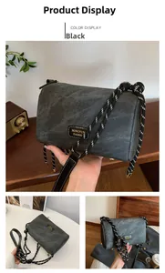 Detail of dark gray crossbody bag with textured fabric, rope strap and metal feet