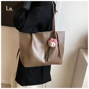 Macro shot of brown faux leather tote bag showing fine stitching and plush charm detail