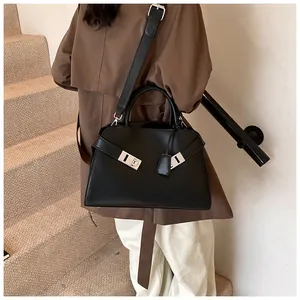 Fashionable black leather handbag with silver lock and shoulder strap worn by a model