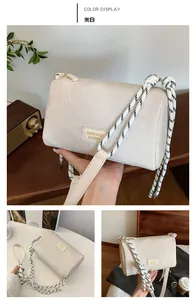 Detailed view of an off-white pillow bag featuring a thick black and white woven strap