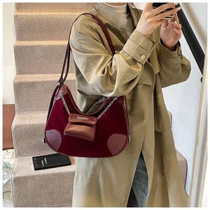 Detalle de bolso hobo de terciopelo burdeos con cadena metálica y mini bolso decorativo