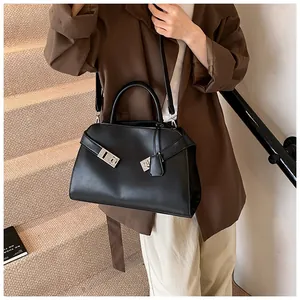 Detail of black leather handbag with silver lock and detachable strap on steps