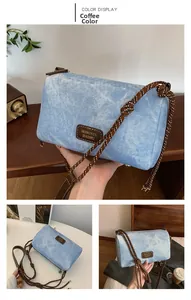Detail of coffee color cylindrical denim bag with braided shoulder strap and leather logo