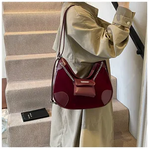 Detalle de bolso hobo de terciopelo granate con cadena plateada y monedero pequeño