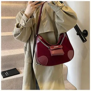 Detalle de bolso media luna granate en cuero con cadena metálica y mini estuche