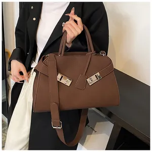Close-up of the silver metal lock and matte leather strap details on a dark brown tote bag