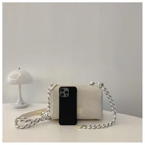Detailed view of off-white envelope bag with rope strap and smartphone for scale
